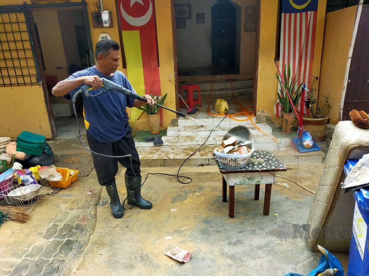 Penduduk Kampung Lembah Jaya Utara, Hassan Mohd Sharif, 56, mencuci barangan rumahnya yang diselaputi lumpur selepas kediaman mereka dilanda banjir kilat. FOTO Muhaamad Hafis Nawawi
