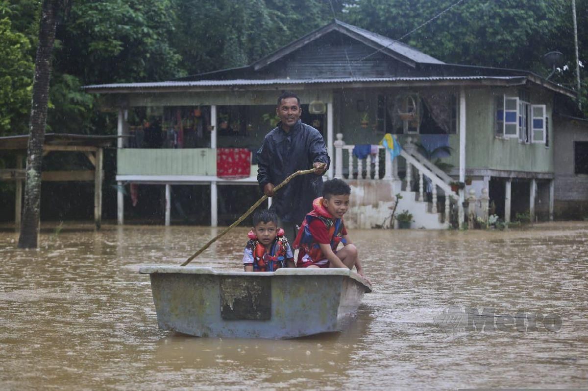Mohd Kamarzaman Isa, 45, (berdiri) mendayung sampan bersama dua anaknya Muhammad Izzat, 8, (kanan) dan Muhammad Hanif, 6, diperkarangan rumahnya yang ditenggelami banjir berikutan hujan lebat sejak beberapa hari lepas ketika tinjauan di Kampung Bukit Tadok. FOTO GHAZALI KORI