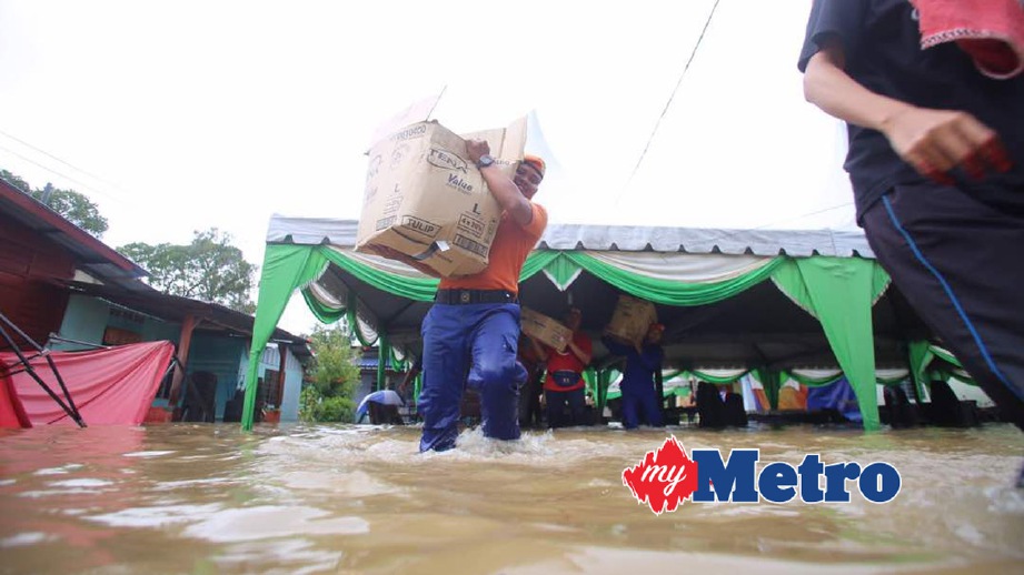 ANGGOTA Angkatan Pertahanan Awam Malaysia (APM) mengangkat barang di rumah mangsa banjir di Kampung Sungai Putat. FOTO Muhammad Zuhairi Zuber