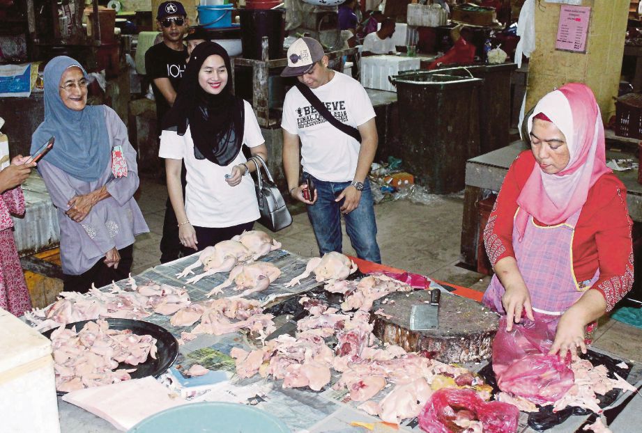 ZARINA  menjual ayam kepada pembeli di Pasar Besar Siti Khadijah, semalam.