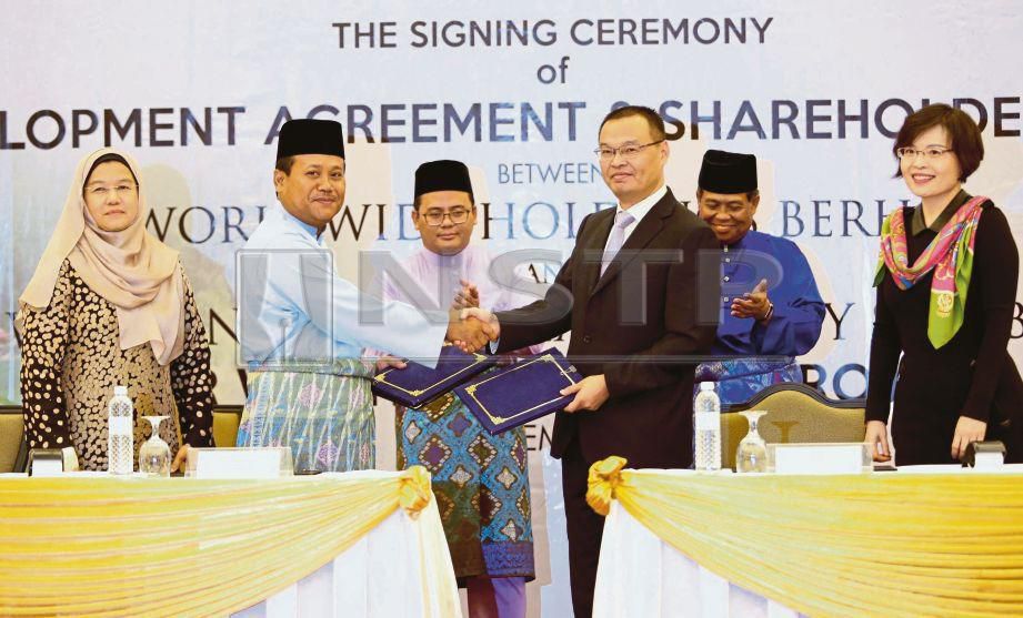 AMIRUDIN  (tengah) menyaksikan pertukaran dokumen perjanjian antara Pengerusi Worldwide Holdings, Datuk Nor  Azmie Diron (dua dari kiri) dengan Wu di  Hotel Concorde Shah Alam, semalam.