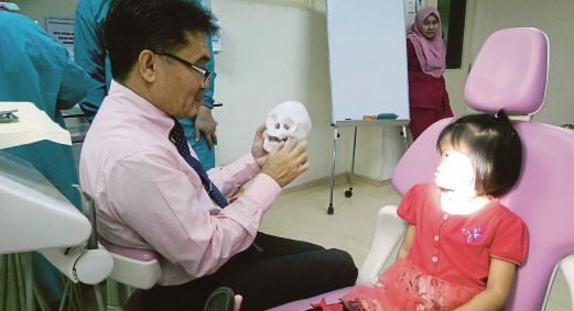 DR ZAINAL Ariff memegang model tengkorak ketika memeriksa keadaan Nurdayana, kelmarin. 