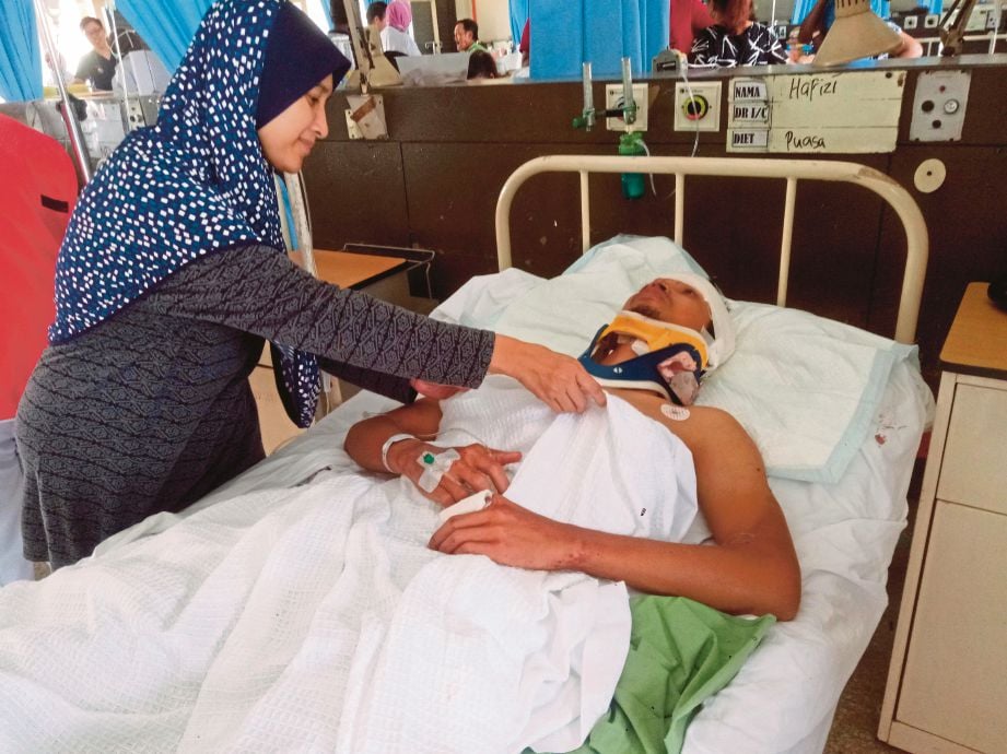 Rosmizar  menemani  Amiruddin yang cedera di bahagian kiri kepala, tengkuk dan tangan mendapat rawatan di Hospital Tengku Ampuan Rahimah, semalam. 