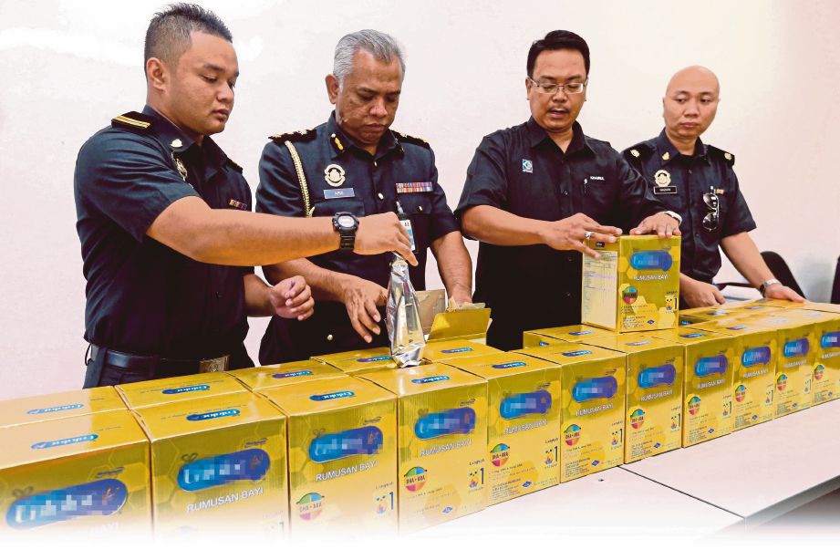 KHAIRUL Anwar (dua dari kanan) bersama pegawai KPDNKK menunjukkan susu rumusan bayi tiruan yang dirampas. 