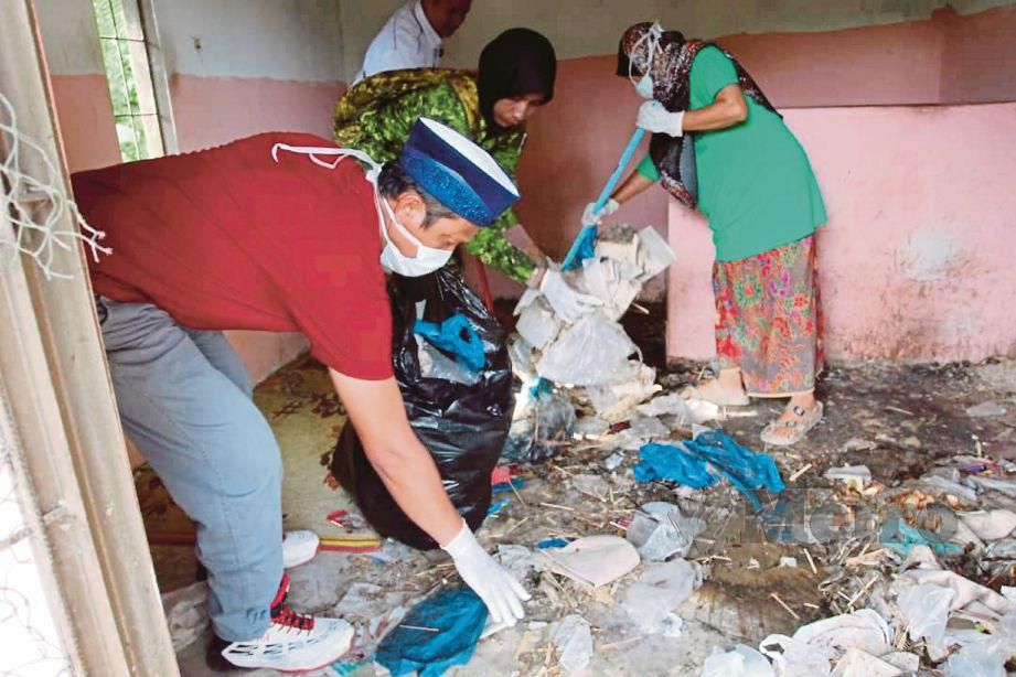 SUKARELAWAN NGO bergotong-royong membersihkan bilik Azuan yang dipenuhi sampah di Kampung Kubang Sawa.