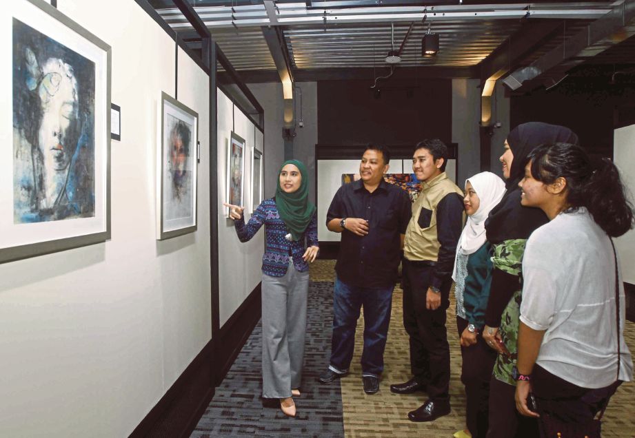 NADDIA (kiri) menerangkan kepada pengunjung mengenai hasil lukisannya pada Pameran Visual Interpretasi Wanita 2016 di Galeri Prima, Balai Berita NSTP.