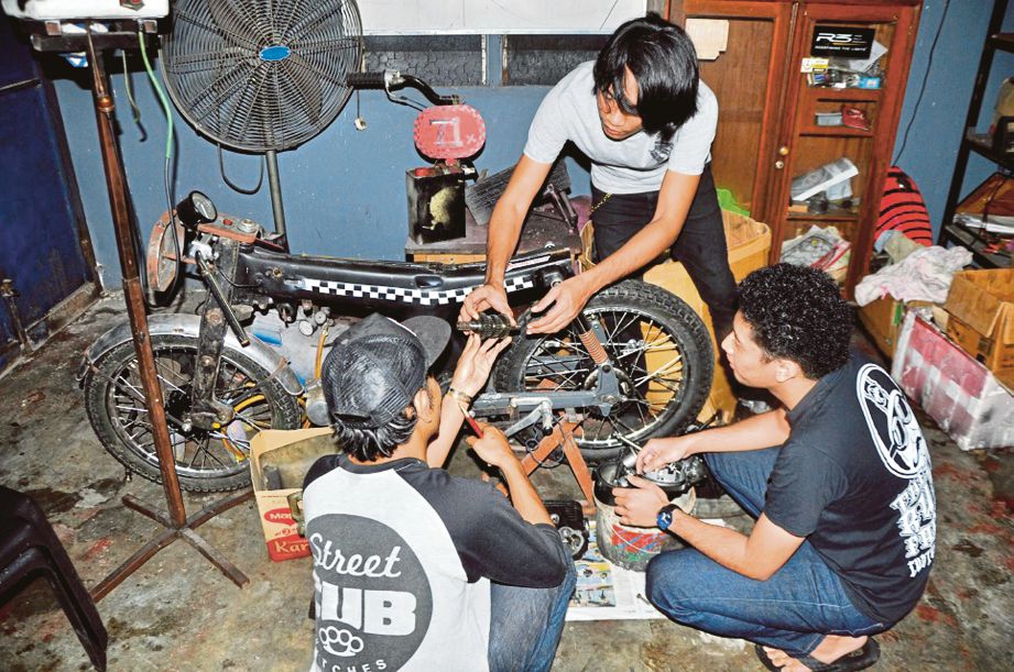 MUHAMMAD Khalid mengajar dua pekerjanya mengubah suai motosikal di bengkel Rusty Factory di Ipoh.