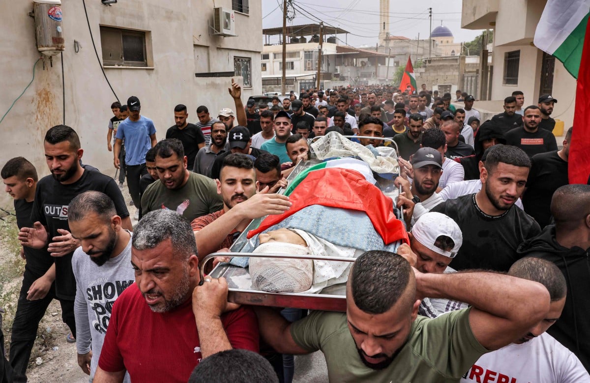 PENDUDUK Palestin mengangkat mayat remaja, Mohamed Fayez Balhan yang maut ditembak tentera Israel di Tebing Barat. FOTO AFP.