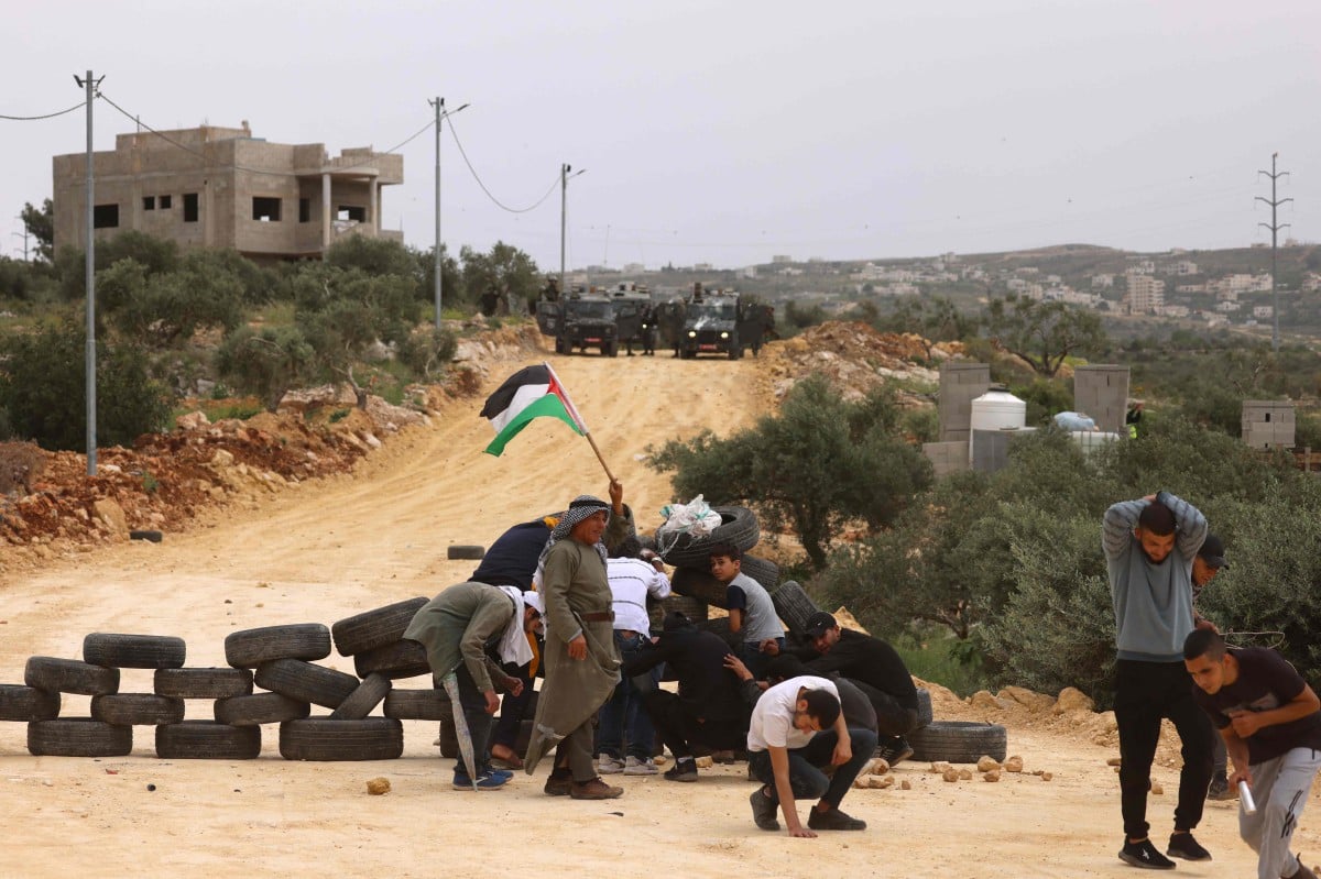 PENDUDUK Palestin membuat benteng dengan tayar di kampung Beita, selatan bandar Nablus, Tebing Barat. FOTO AFP.