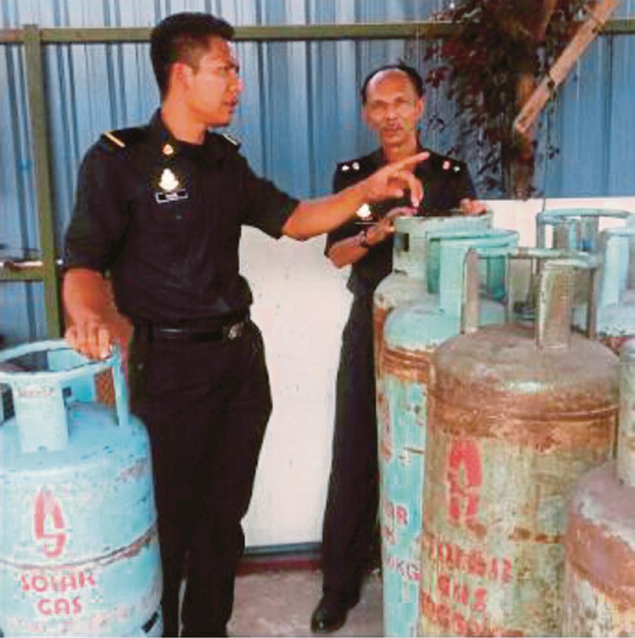 ANGGOTA KPDNKK Selangor memeriksa LPG yang dirampas dalam serbuan, kelmarin.