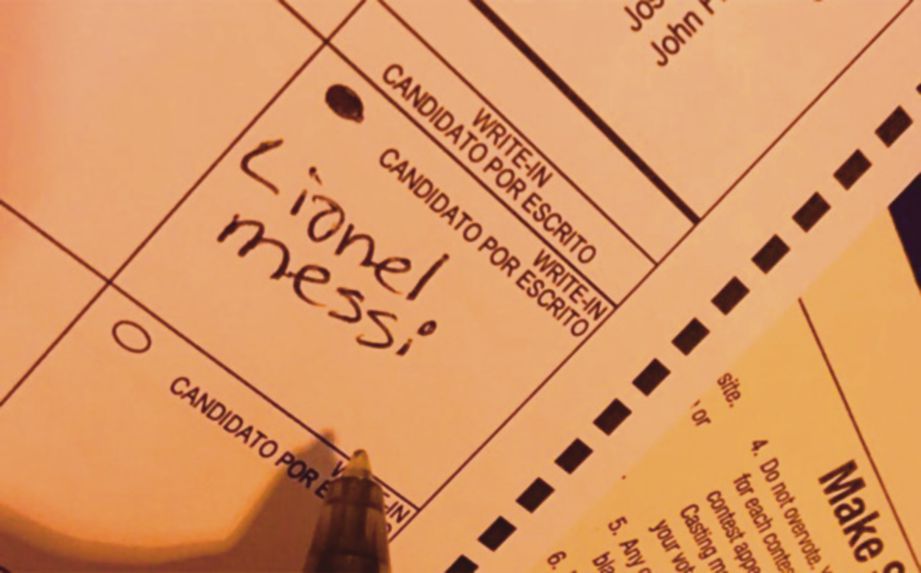  SEORANG pengundi mengisi nama Messi pada kertas undi. 