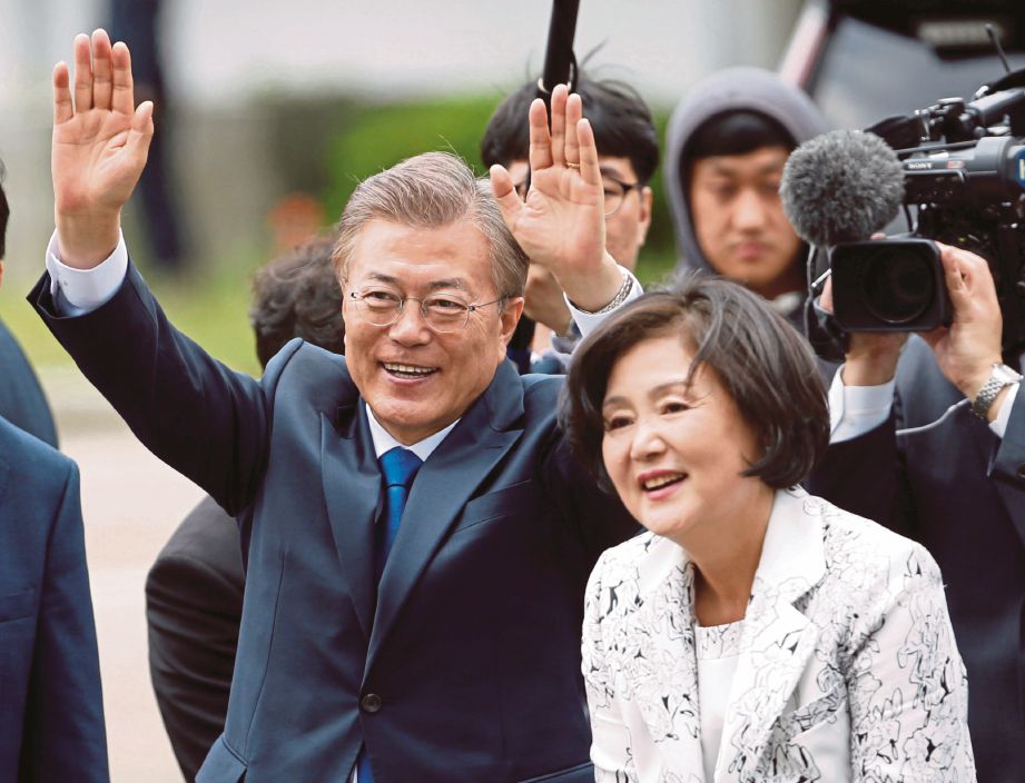 MOON  dan isteri, Kim Jung-sook melambai kepada orang ramai ketika tiba di majlis angkat sumpah di Rumah Biru, Seoul. - Reuters 