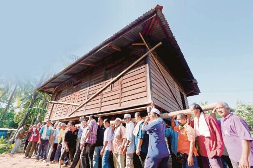 PENDUDUK mengangkat rumah pusaka milik Haron di Kampung Titi Serong, Jalan Dulang. 