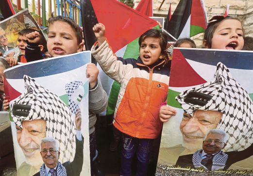 KANAK-kanak Palestin membawa gambar bekas pemimpin, Yasser Arafat dan Presiden Mahmoud Abbas dalam perhimpunan memperingati ulang tahun ke-11 kematian Arafat di Hebron.