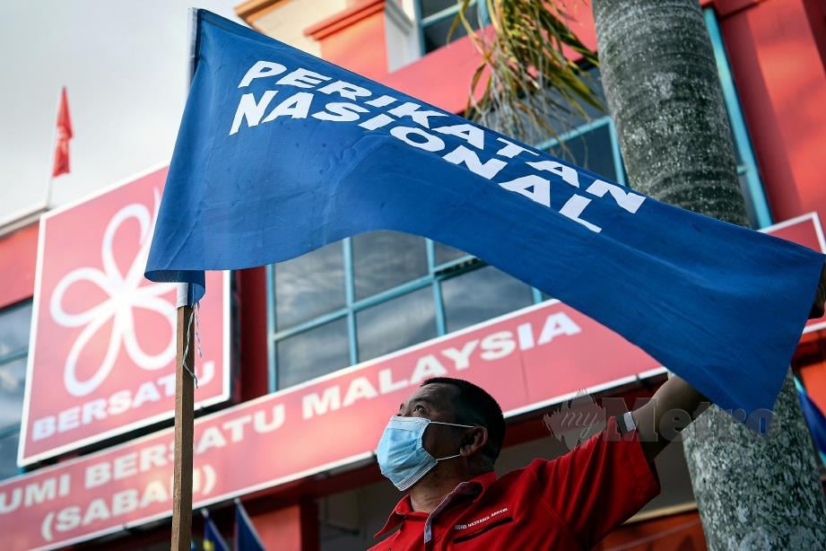 PENYOKONG PN memasang bendera parti selepas Majlis Pengumuman Calon Perikatan Nasional (PN) Sabah di Pejabat Bersatu Sabah, semalam. FOTO Bernama