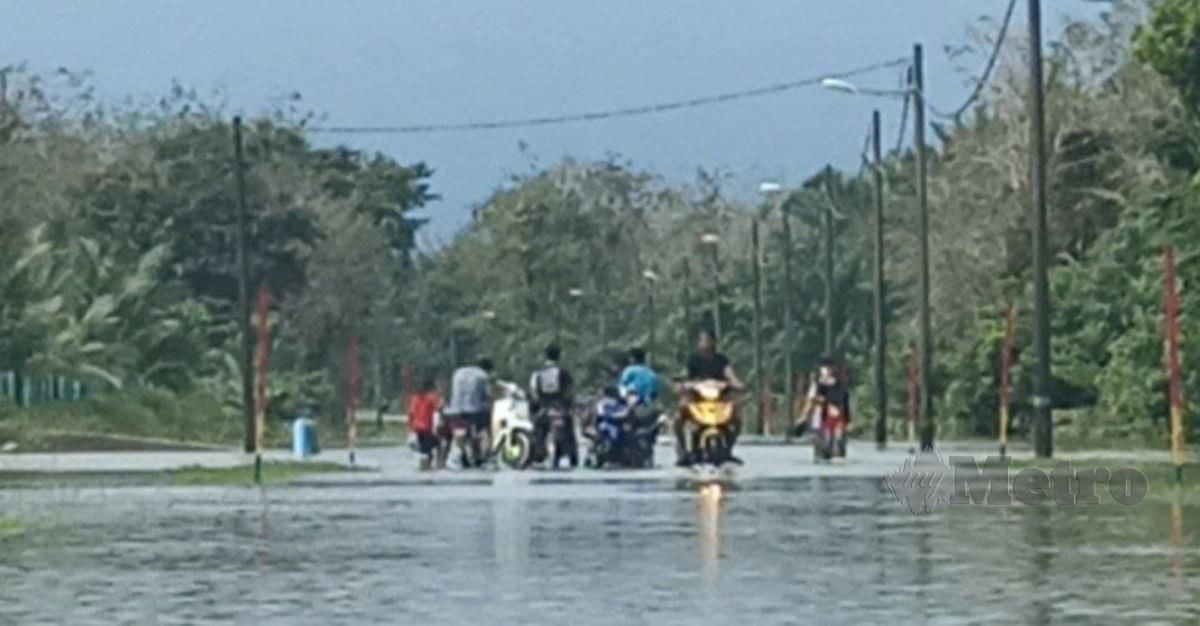 Penduduk bermain air banjir di Jalan Ulu Seladang - Permaisuri yang surut berikutan cuaca yang semakin baik. FOTO ZAID SALIM