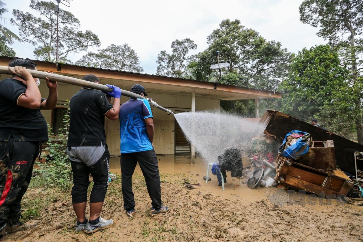 Anggota FRU turut serta membantu  penduduk membersih rumah yang ditenggelami banjir di Batu 18 Hulu Langat. FOTO ASWADI ALIAS