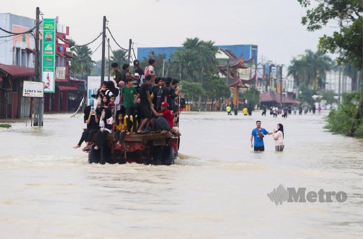  Penduduk Pekan Rantau Panjang menggunakan lori untuk meredah laluan yang dinaiki air bah. FOTO NIK ABDULLAH NIK OMAR