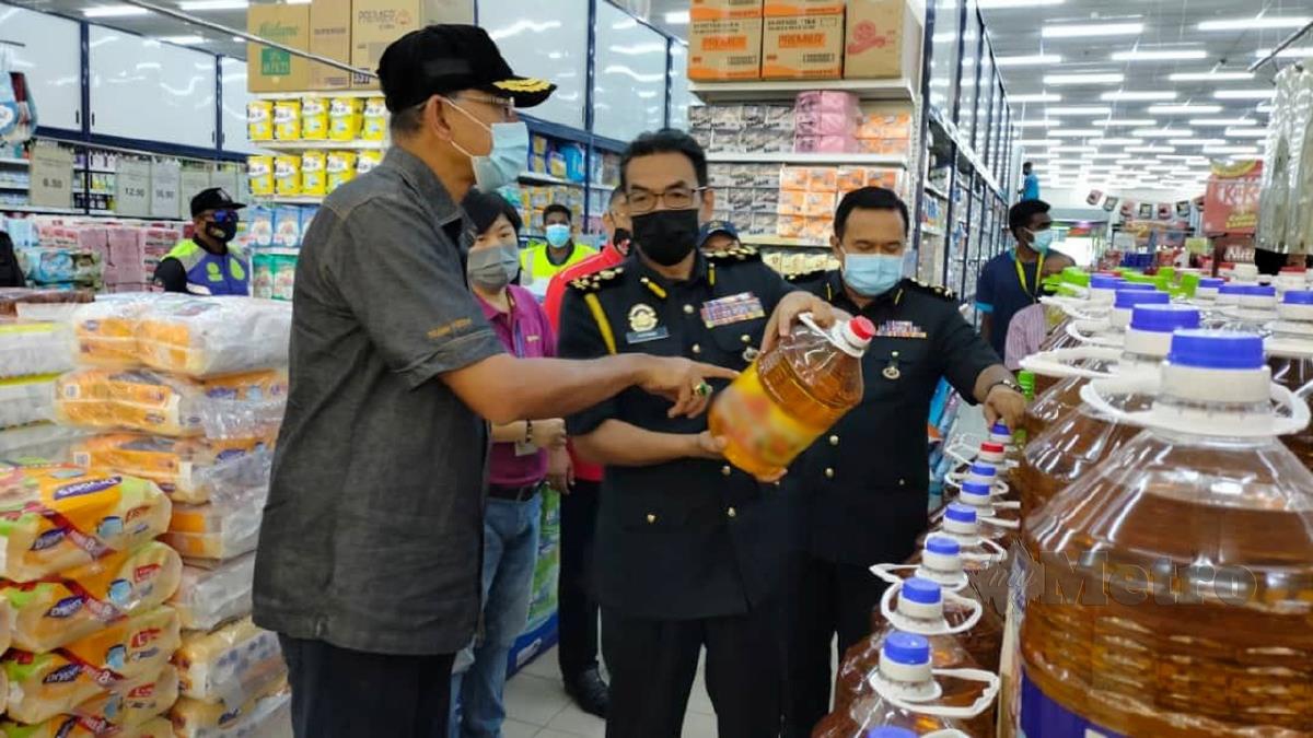 ROSOL (kiri) melihat harga minyak masak botol yang dipegang oleh Pengarah Penguat Kuasa KPDNHEP, Azman Adam (tengah) ketika pemeriksaan pematuhan SOP Akta 342 dan bekalan minyak masak di pasar raya. FOTO Amirul Aiman Hamsuddin