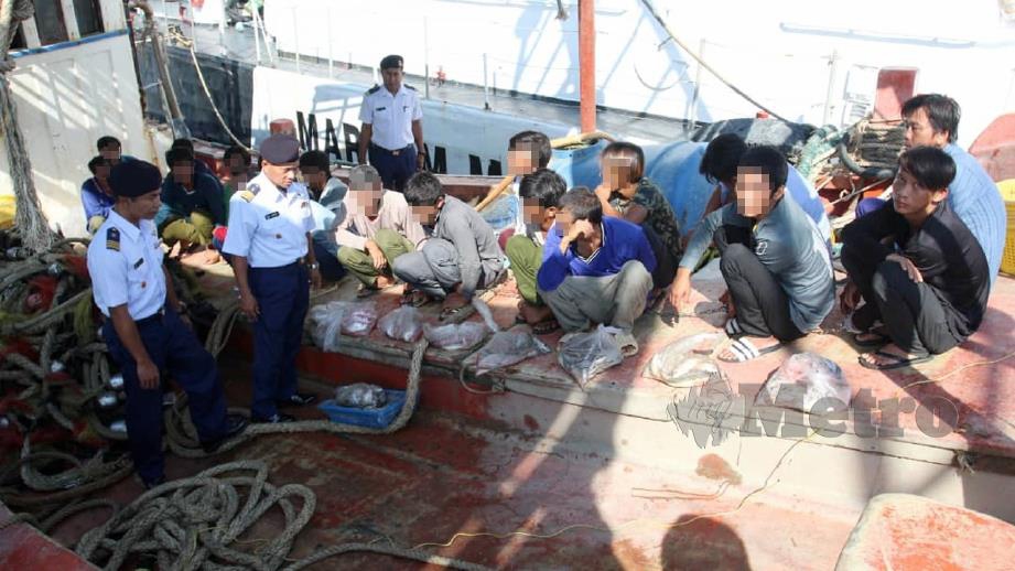 ISMAIL (dua kiri) bersama pegawai memeriksa 21 nelayan asing Vietnam yang ditahan bersama dua bot 97 batu nautika dari Kuala Tok Bali. FOTO Nik Abdullah Nik Omar