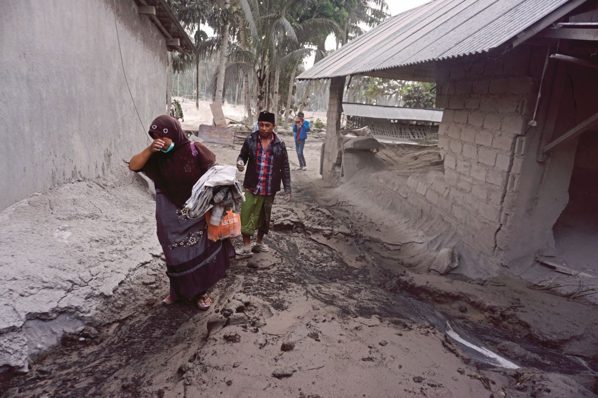 PENDUDUK mengusung barangan dari rumah mereka selepas letusan Gunung Semeru. FOTO EPA 