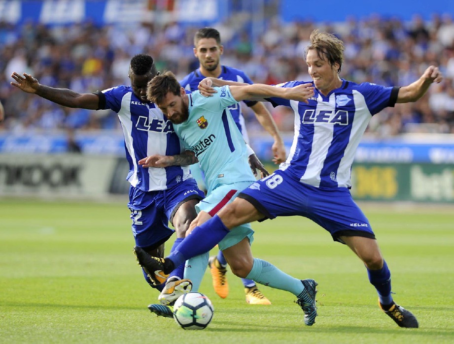  Messi (tengah) cuba lepas kawalan ketat pemain Alaves. -Foto AFP 