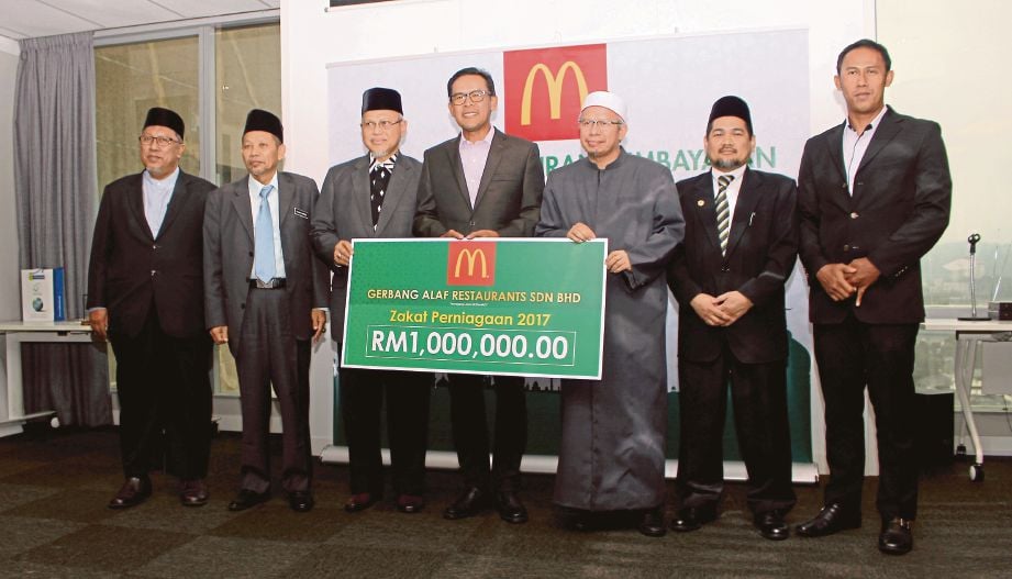 AZMIR  (tengah)  bersama  Zulkifli   (dua dari kanan) dan wakil penerima zakat di bangunan Tabung Haji di Damansara, semalam.