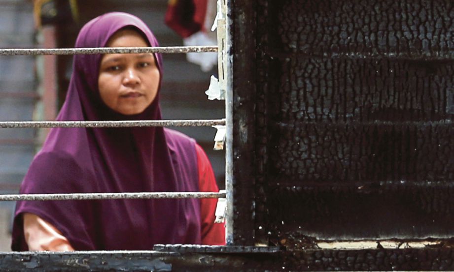  Siti Zainab  melihat rumahnya yang terbakar.