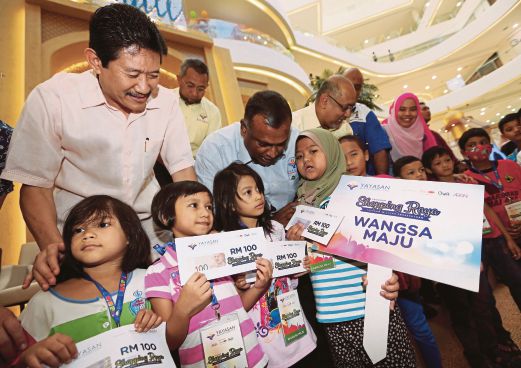 TIMBALAN Menteri Wilayah Persekutuan Datuk Dr Loga Bala Mohan (dua kiri) beramah mesra dengan kanak-kanak pada program beli-belah raya Yayasan Wilayah Persekutuan.