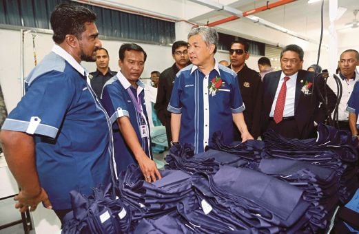 AHMAD Zahid (tengah) melihat produk yang dihasilkan selepas merasmikan bangunan operasi Balqis Textiles And Manufacturing Sdn Bhd.