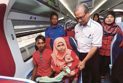 Mohamad Sejawi (kiri) bersama isteri Nurbustaniah yang memegang anaknya, Nurhidayah Fatihah sambil diperhatikan Pengurus Kebajikan dan Perhubungan Pekerja KTMB, Abdul Rahim Osman (kanan) di Arau.