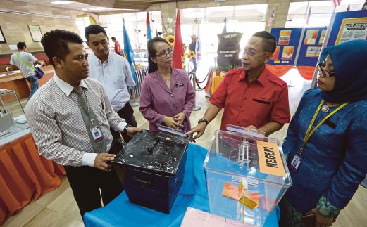 Takun (dua dari kanan) mendengar penerangan mengenai sejarah pilihan raya   anjuran Arkib Negara di Bangunan Sultan Iskandar, Kuching.