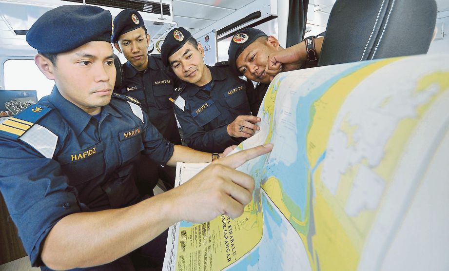 MOHD Hafidz (kiri) bersama pegawainya melihat peta di dalam KM Kota Belud di Pelabuhan Sabah, semalam.