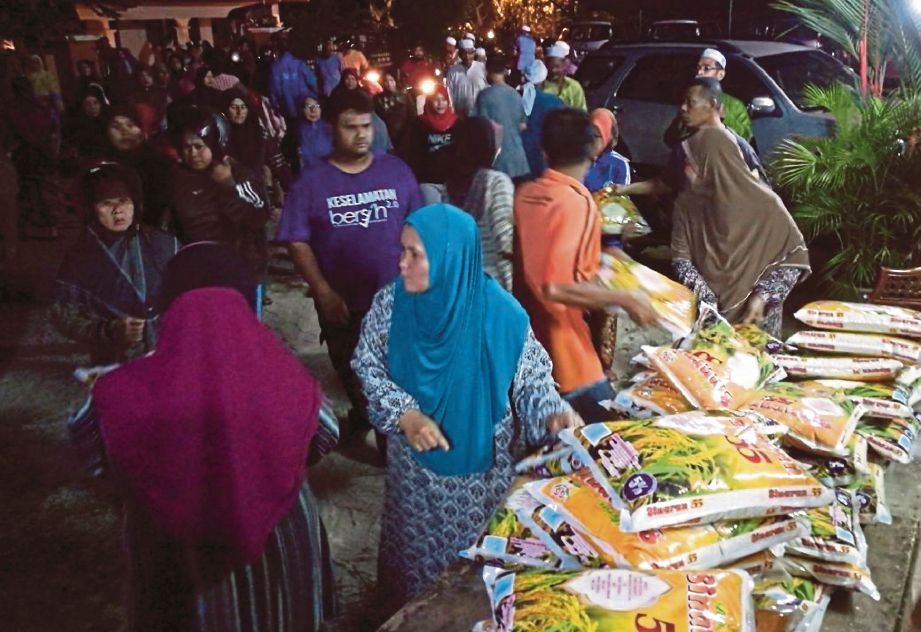 ORANG ramai mengambil beras percuma  yang  disumbangkan   Abdul  Ghani dan rakan FB   di pekarangan rumahnya di Kampung Masjid, Tikam Batu.  