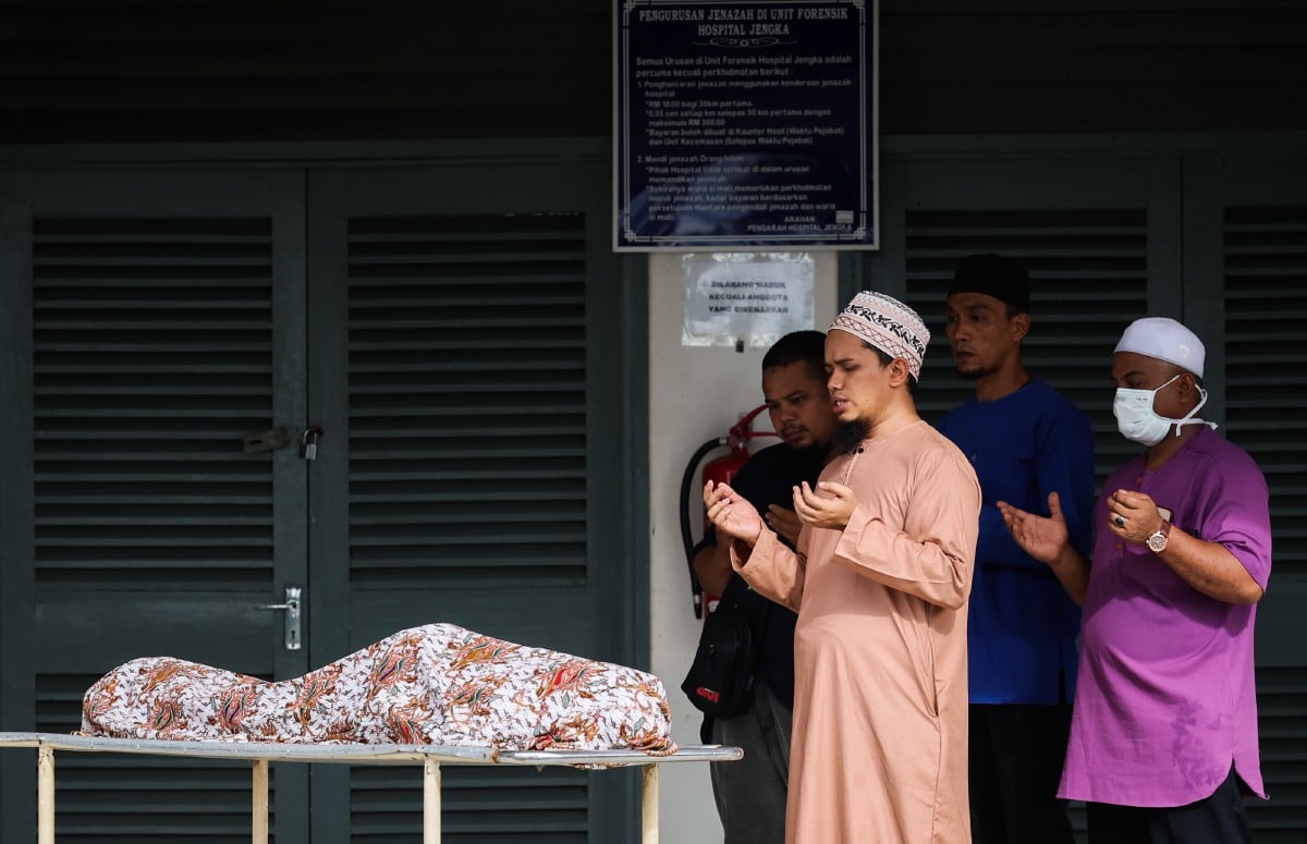 HUZAIFAH Muhammad, 30, (tiga, kanan) membaca doa selepas mengimamkan solat jenazah seorang daripada tiga beradik yang maut dalam kemalangan di LPT1, pagi tadi. FOTO Bernama.
