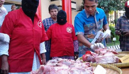 SEORANG anggota polis memeriksa daging babi yang dijual sebagai daging lembu di sebuah pasar di Surabaya.