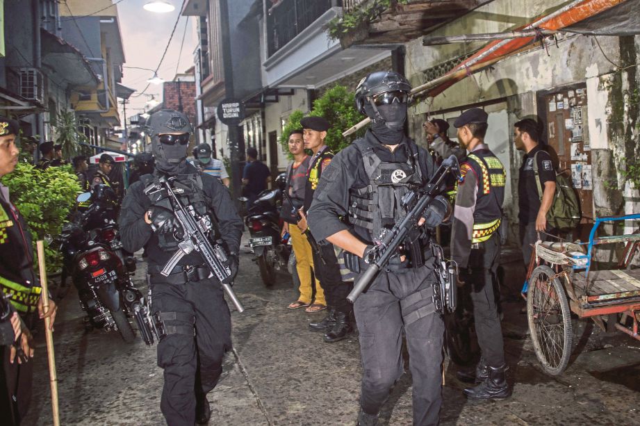 ANGGOTA polis dari unit antipengganas melakukan serbuan di sebuah rumah di Surabaya kelmarin untuk menangkap suspek militan. - AFP