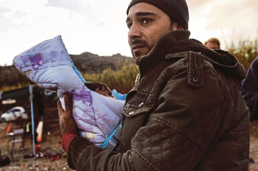 SEORANG pelarian mendukung bayinya ketika selamat tiba di Pulau Lesbos selepas melintas Laut Agean dari Turki.
