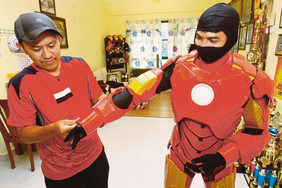 MOHD Faizal dibantu rakannya memakai sut adiwira Iron Man.