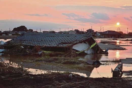 MATAHARI terbenam di belakang rumah yang musnah dan ditenggelami banjir di bandar Joso, semalam.   
