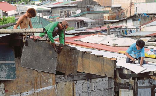 PENDUDUK di Teluk Manila membaiki bumbung kediaman mereka yang rosak akibat ribut yang berpunca daripada taufan Noul, kelmarin.