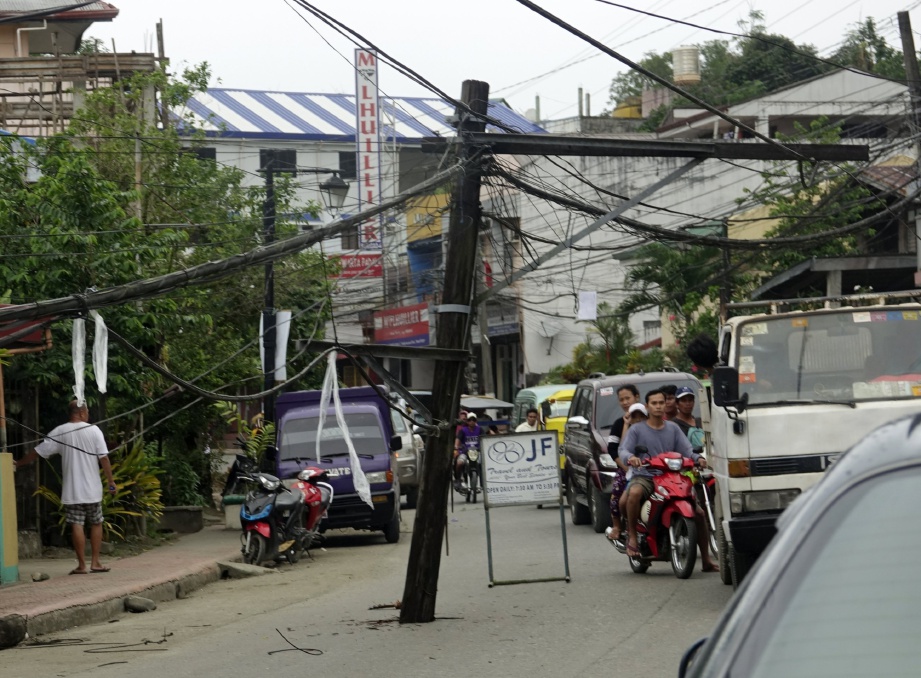 PENGGUNA jalan raya mengelak tiang elektrik yang hampir tumbang akibat gempa bumi. - EPA