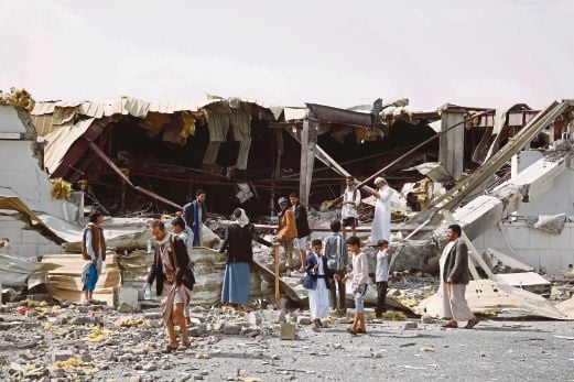 SEKUMPULAN penduduk melihat kilang pakaian yang musnah dalam serangan udara di Sanaa, kelmarin.