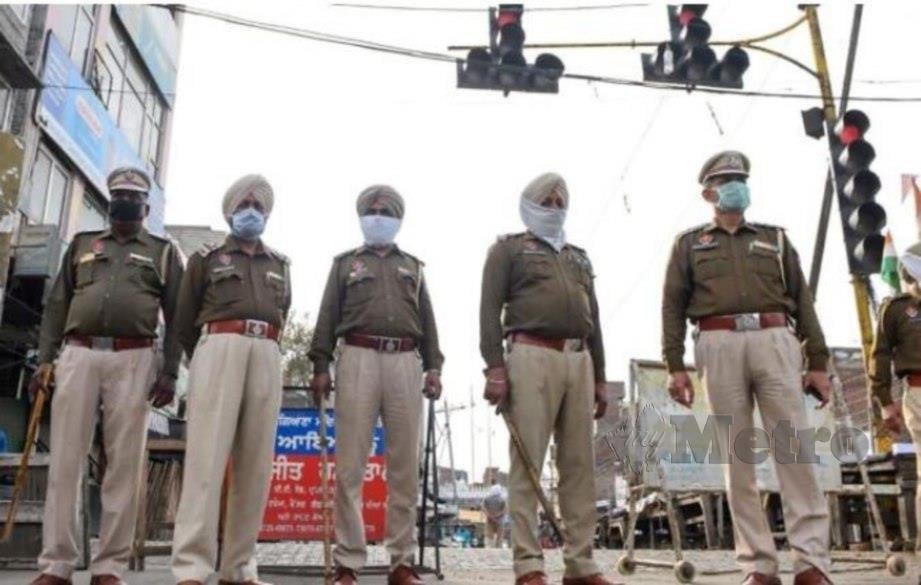 POLIS mengawal persimpangan lampu isyarat di India. 