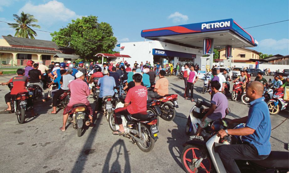 SEBAHAGIAN daripada pengguna motosikal beratur menunggu giliran isian minyak percuma.