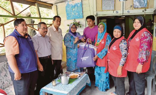 QAIRIL Azry menerima sumbangan  JKM sebanyak RM200 daripada Norhayati (empat dari kiri)