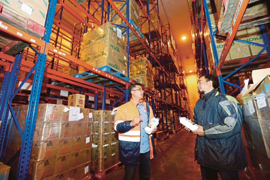 Azmi  (kiri) memeriksa produk tenusu keluaran syarikatnya ketika membuat lawatan ke gudang sejuk beku sebelum diedarkan kepada penjual di seluruh negara.