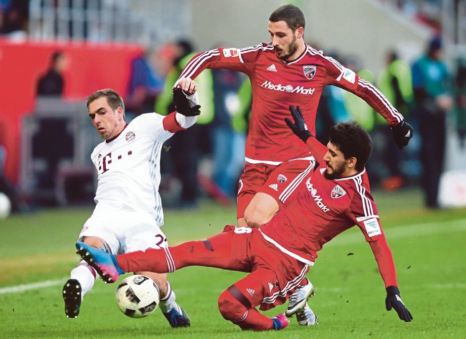 PEMAIN Bayern, Philipp Lahm (kiri) diasak dua pemain  Ingolstadt. 