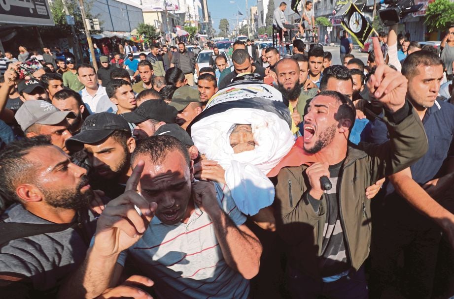 PENDUDUK membawa mayat Baha Abu Al-Atta (gambar kecil) untuk dikebumikan. FOTO Reuters
