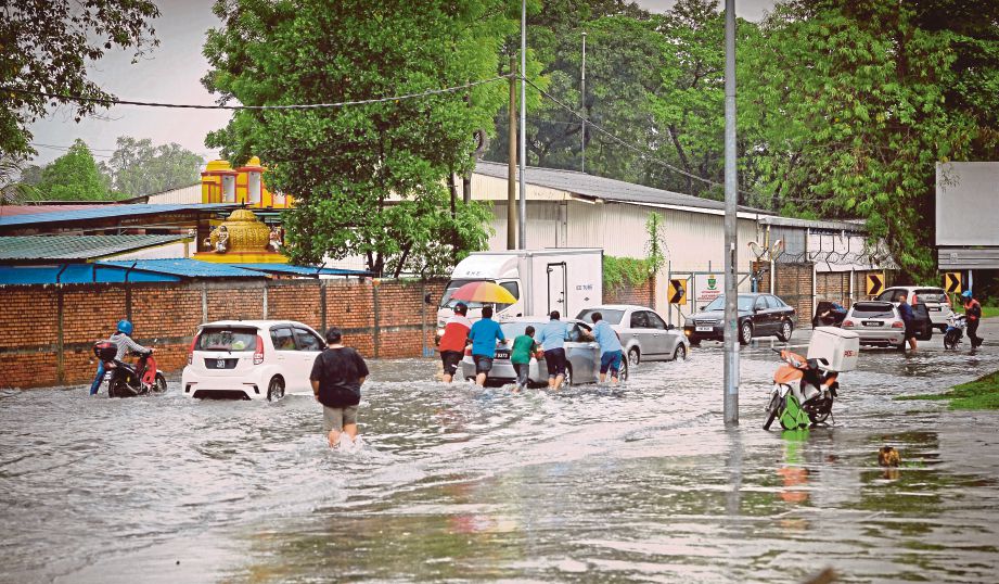 ORANG ramai menolak kereta yang tersangkut di dalam banjir di Jalan Kampung Pandan. 